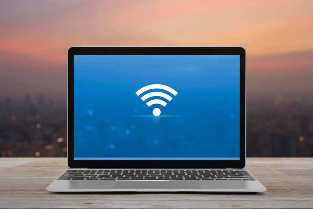Laptop with Wi-Fi symbol on the screen with a city view in the background.