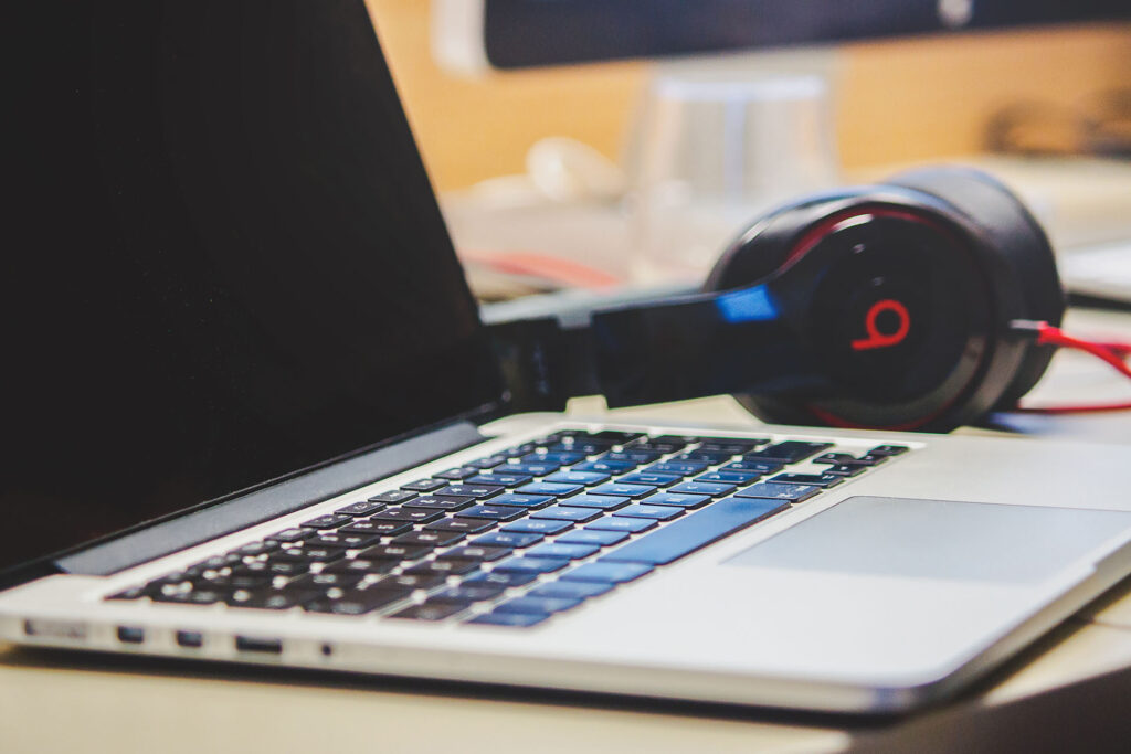 A laptop and headphones sit on a desk.