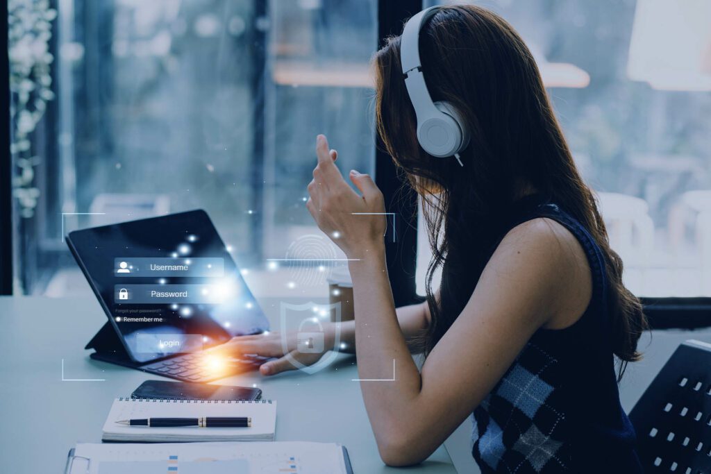 A woman sits at a desk, listening to music and using the internet.