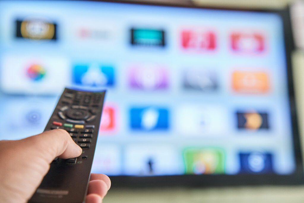 Person holding a remote control that is pointed at a smart tv.