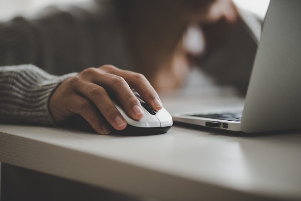 Person using a mouse and a laptop placed on a smooth surface.