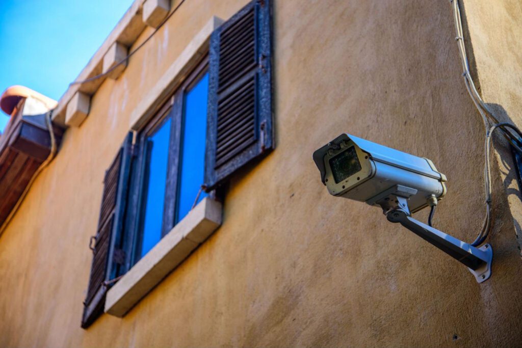 Security camera on the outside of a house with a view of a window with shutters.