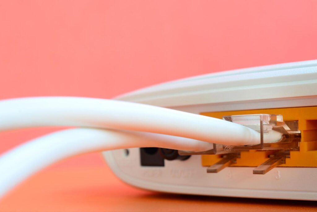 Internet plugs connected to a white router against a pink background.