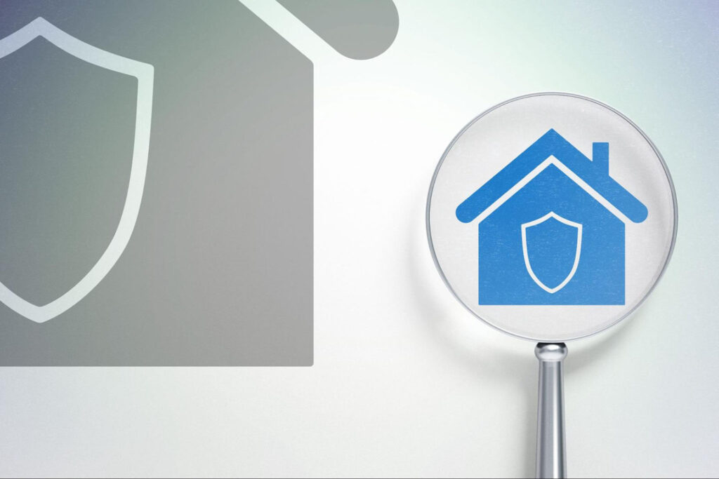 Outline of a home with a shield icon and a magnifying glass hovering over.