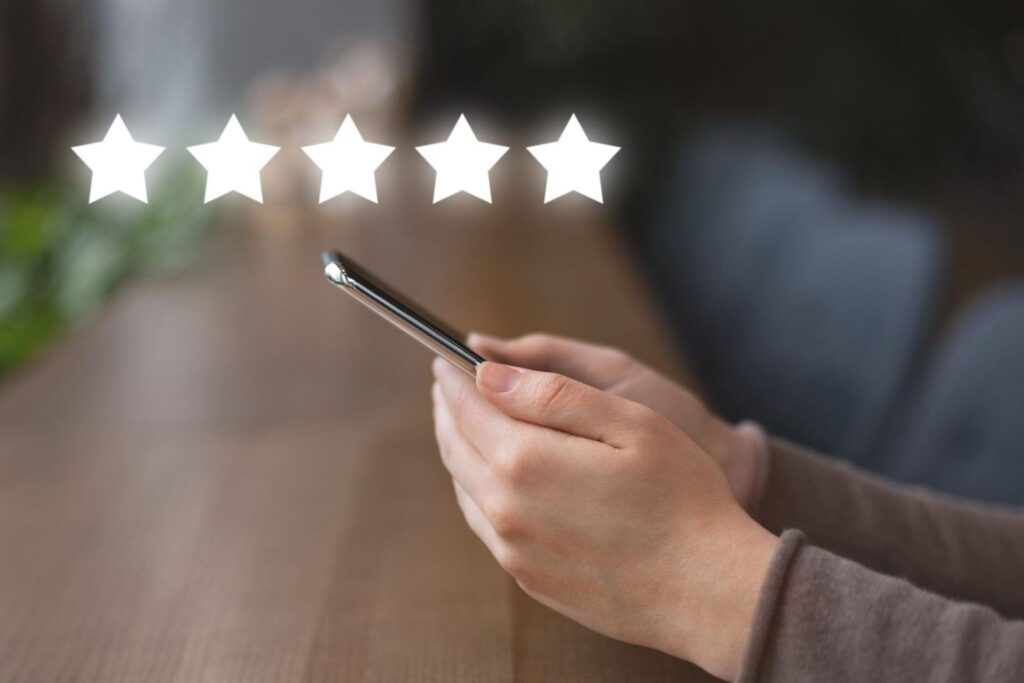 Person holding a phone with five star icons floating above.