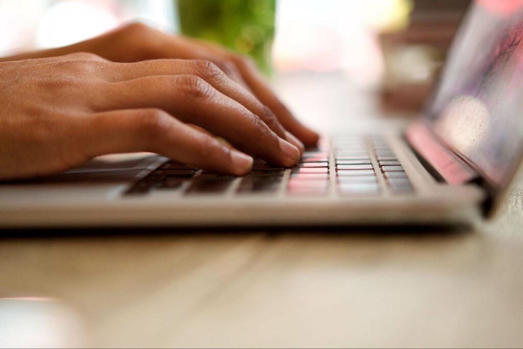 Person typing on a laptop on a smooth surface.