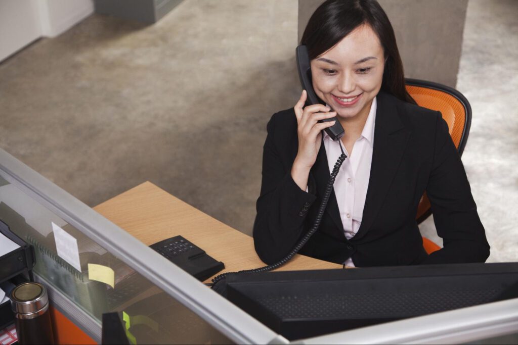 A businesswoman makes a phone call on a landline.