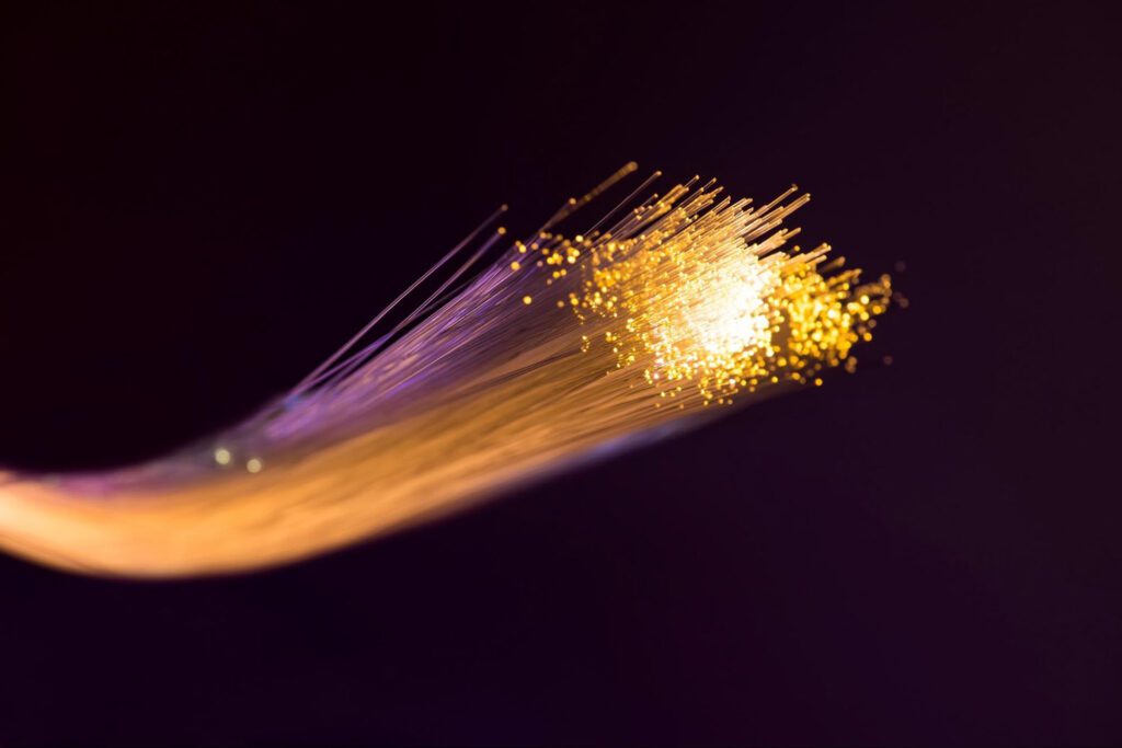 A close-up of a fiber optic cable glowing with a soft yellow color.