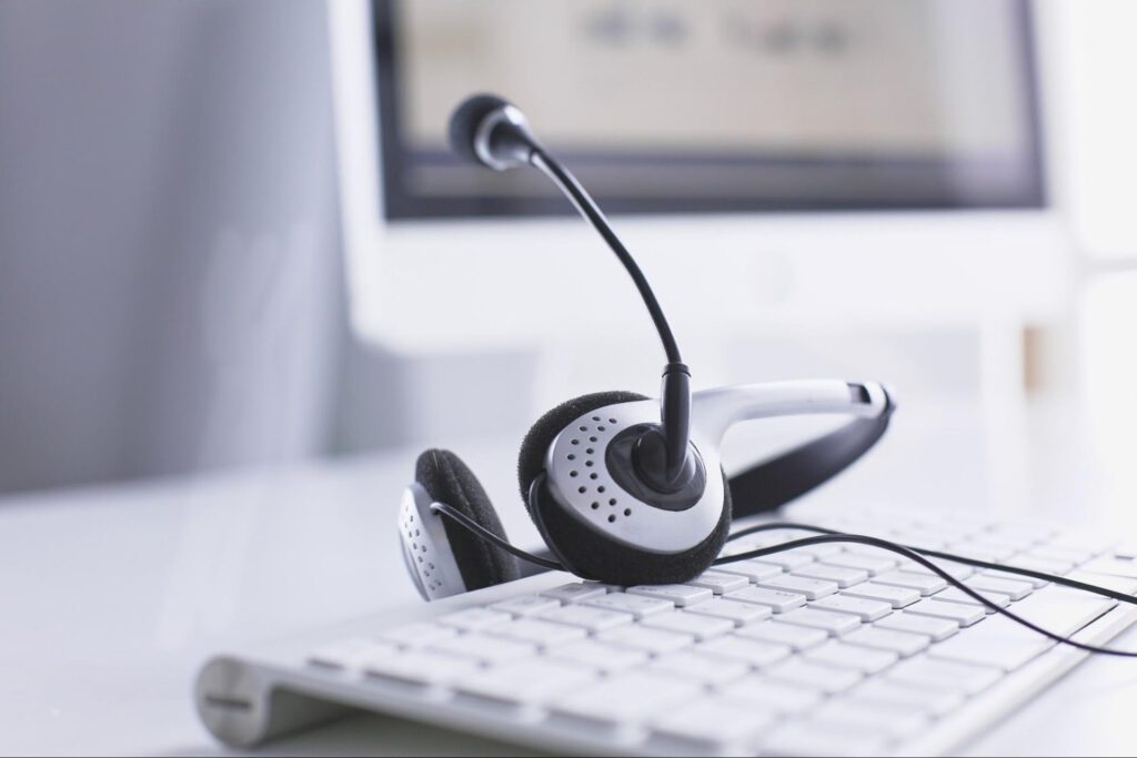 A customer service headset rests on a keyboard in an office setting.