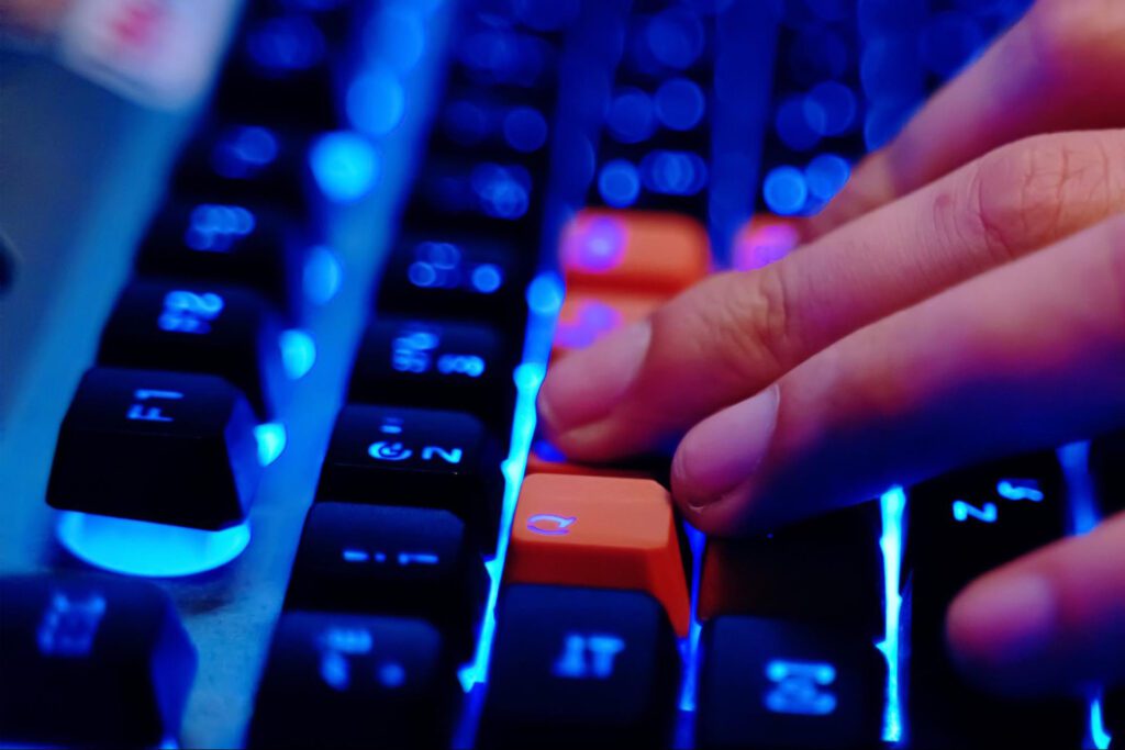 A close-up view of a person typing on a lit-up gaming keyboard.