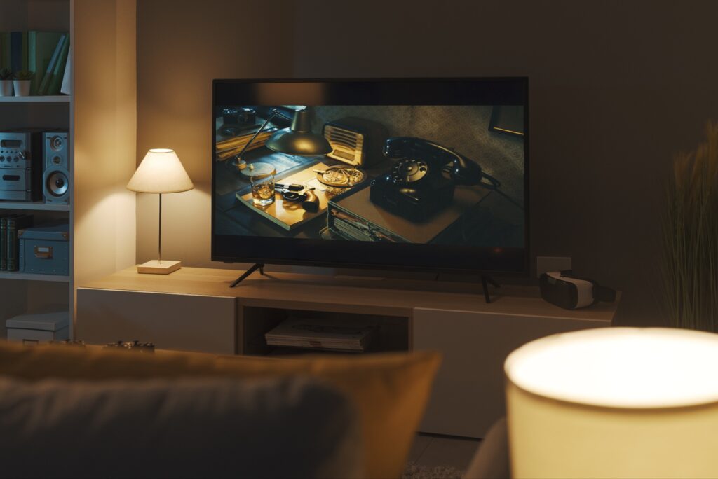 A view of a cozy, dimly-lit living room with a noir scene on the screen. 