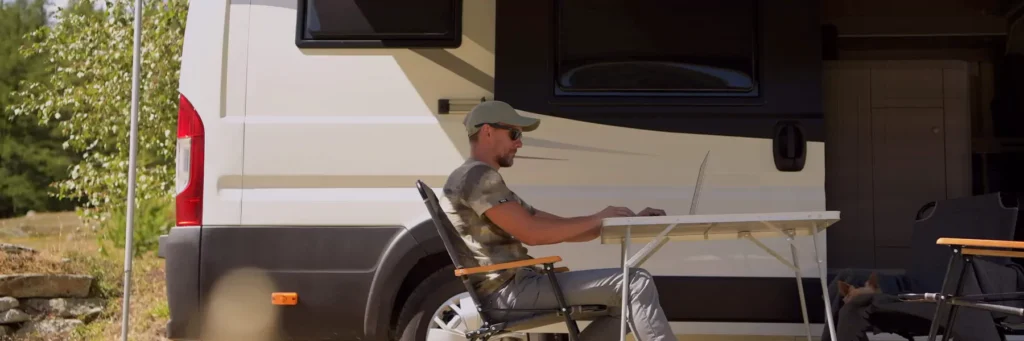 someone using computer or phone outside of an RV